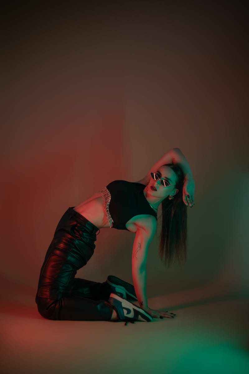 A woman in black leather pants and a red and green light